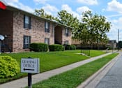 Thumbnail 6 of 7 - a leasing office sign in front of a brick apartment building at Archer Village Apartments,Sherman, TX,