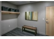 Thumbnail 2 of 10 - A room with a wooden bench, a painting on the wall, and a door.
