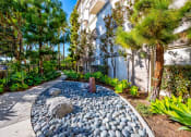 Thumbnail 60 of 74 - a walkway with rocks and trees in front of a building
