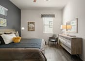 Thumbnail 11 of 36 - A bedroom with a bed, chair, and dresser.