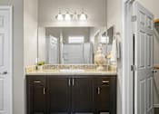 Thumbnail 13 of 36 - A bathroom with a granite countertop and a vanity with a plant on it.
