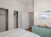 Thumbnail 17 of 36 - A room with a bed, a cabinet, and a painting on the wall.