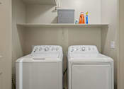 Thumbnail 18 of 36 - Two white front loading washing machines in a small laundry room.