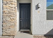Thumbnail 21 of 36 - A house with a black door and a stone pillar on the left.