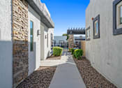 Thumbnail 22 of 36 - A narrow alley with a stone wall on the left and a white wall on the right with a window.