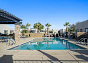 Thumbnail 25 of 36 - A swimming pool with a slide and palm trees in the background.