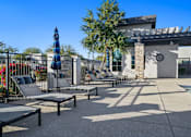 Thumbnail 29 of 36 - A poolside area with sun loungers and a shade structure.