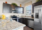 Thumbnail 2 of 36 - A kitchen with granite countertops and stainless steel appliances.