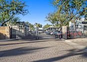 Thumbnail 35 of 36 - A gated entrance to a parking lot with a building in the background.