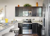 Thumbnail 3 of 36 - A modern kitchen with dark wood cabinets and stainless steel appliances.