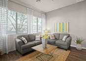 Thumbnail 7 of 36 - A living room with a grey couch, a coffee table, and a painting on the wall.