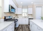 Thumbnail 54 of 60 - a kitchen with white cabinets and a stove and a microwave