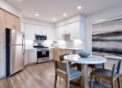 Thumbnail 22 of 33 - a kitchen with stainless steel appliances and a round table with chairs