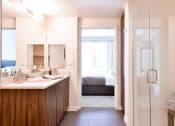 Thumbnail 30 of 33 - a bathroom with a shower and sink and a bedroom with a bed
