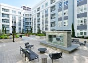 Thumbnail 17 of 33 - a patio with a fire pit in front of an apartment building