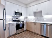 Thumbnail 23 of 33 - a modern kitchen with white cabinets and stainless steel appliances
