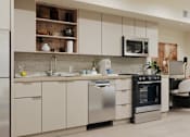 Thumbnail 47 of 117 - A modern kitchen with stainless steel appliances and white cabinets at Skyview Sunset Apartments, Los Angeles