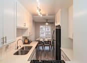 Thumbnail 10 of 27 - A kitchen with white cabinets and a black refrigerator at Nola 624 Apartments, West Covina, CA, 91790