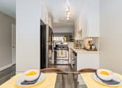Thumbnail 8 of 27 - A modern kitchen with a black refrigerator and a breakfast table set with two bowls of fruit at Nola 624 Apartments, California