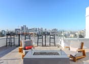 Thumbnail 9 of 33 - a rooftop terrace with chairs and a fire pit and a city in the background
