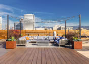Thumbnail 24 of 30 - Luxury Studio Apartments Downtown Oakland CA - Alice House - Rooftop Terrace with Wooden Fencing, Plant Boxes, Seating Area with Couches and String Lights Overhead, and Beautiful Cityscape Views