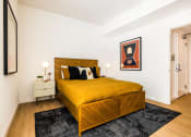Thumbnail 5 of 30 - One Bedroom Luxury Apartments in Downtown Oakland CA - Alice House - Furnished Bedroom with a Wooden Bed, Hardwood Style Flooring, Rug, Two Cream Nightstands with Drawers and Lamps, and White Walls
