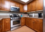 Thumbnail 15 of 75 - a kitchen with wood cabinets and stainless steel appliances