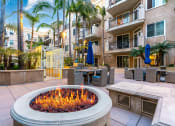Thumbnail 33 of 75 - a fire pit in the middle of a patio with tables and umbrellas