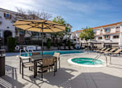 Thumbnail 6 of 46 - A poolside table and chairs are set up under a yellow umbrella.