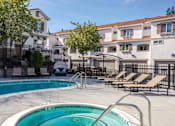 Thumbnail 4 of 46 - A pool with a ladder and chairs in front of apartment buildings.