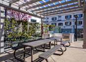 Thumbnail 17 of 46 - A patio with a table and benches under a pergola.