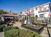 Thumbnail 9 of 46 - A white building with a red roof and a garden in front.