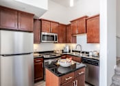 Thumbnail 3 of 46 - A kitchen with brown cabinets and a stainless steel refrigerator.