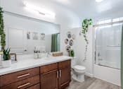 Thumbnail 20 of 46 - A bathroom with a white countertop and a green plant.