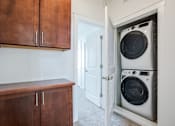 Thumbnail 21 of 46 - A white washing machine is in a cabinet in a room.