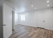 Thumbnail 46 of 46 - A room with white walls and wooden flooring with two doors.