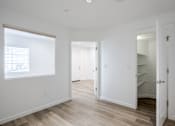 Thumbnail 44 of 46 - A white room with a window and a door leading to another room.