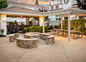 Thumbnail 25 of 32 - A patio with a fire pit and seating area.