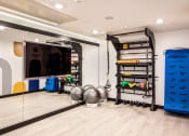 Thumbnail 17 of 30 - a home gym with a television and weights and a punching bag