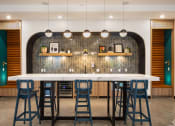 Thumbnail 12 of 30 - a large bar with blue stools in front of a white counter top