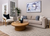 Thumbnail 38 of 98 - Spring Valley, NV, Apartments for Rent in 89147 - Alicante - Spacious Living Room With Neutral Sofa, Round Coffee Table, Ceiling Fan, And Adjacent Dining Nook With Large Windows And Curtains.