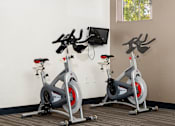 Thumbnail 19 of 98 - an indoor gym with three exercise bikes and a picture of a man with his arms