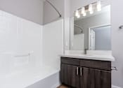 Thumbnail 69 of 98 - a bathroom with a white tub and a sink and a mirror