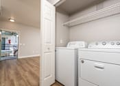 Thumbnail 74 of 98 - Apartments for Rent in 89147, Spring Valley, NV - Alicante - Bathroom with Hardwood-Style Floor, Bathtub, Wood-Tone Cabinet, Mirror, and Laundry Closet with Washer and Dryer