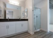 Thumbnail 26 of 29 - Oakland CA Apartments-Aqua Via Apartments Bathroom With Glass Door Shower And Double Sink Vanity And Vinyl Plank Flooring at Aqua Via Apartments, Oakland, California