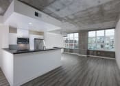 Thumbnail 20 of 29 - Kitchen with stainless steel appliances and living area with large windows at Aqua Via Apartment, California