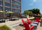 Thumbnail 13 of 29 - Apartments for Rent in Oakland - Aqua Via - Courtyard with Chairs, Umbrellas, BBQ Area, Grills, and Picnic Tables at Aqua Via Apartments, Oakland, California