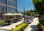 Thumbnail 16 of 29 - a patio with tables and umbrellas on a sunny day at Aqua Via Apartments, Oakland, 94607