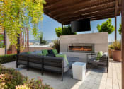 Thumbnail 14 of 29 - Oakland Apartments for Rent - Aqua Via - Community Patio with a Fireplace, a TV, and Lounge Chairs at Aqua Via Apartment, California