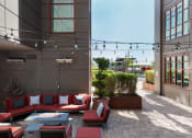 Thumbnail 15 of 29 - a patio with couches and a firepit in front of a building at Aqua Via Apartments, Oakland, 94607